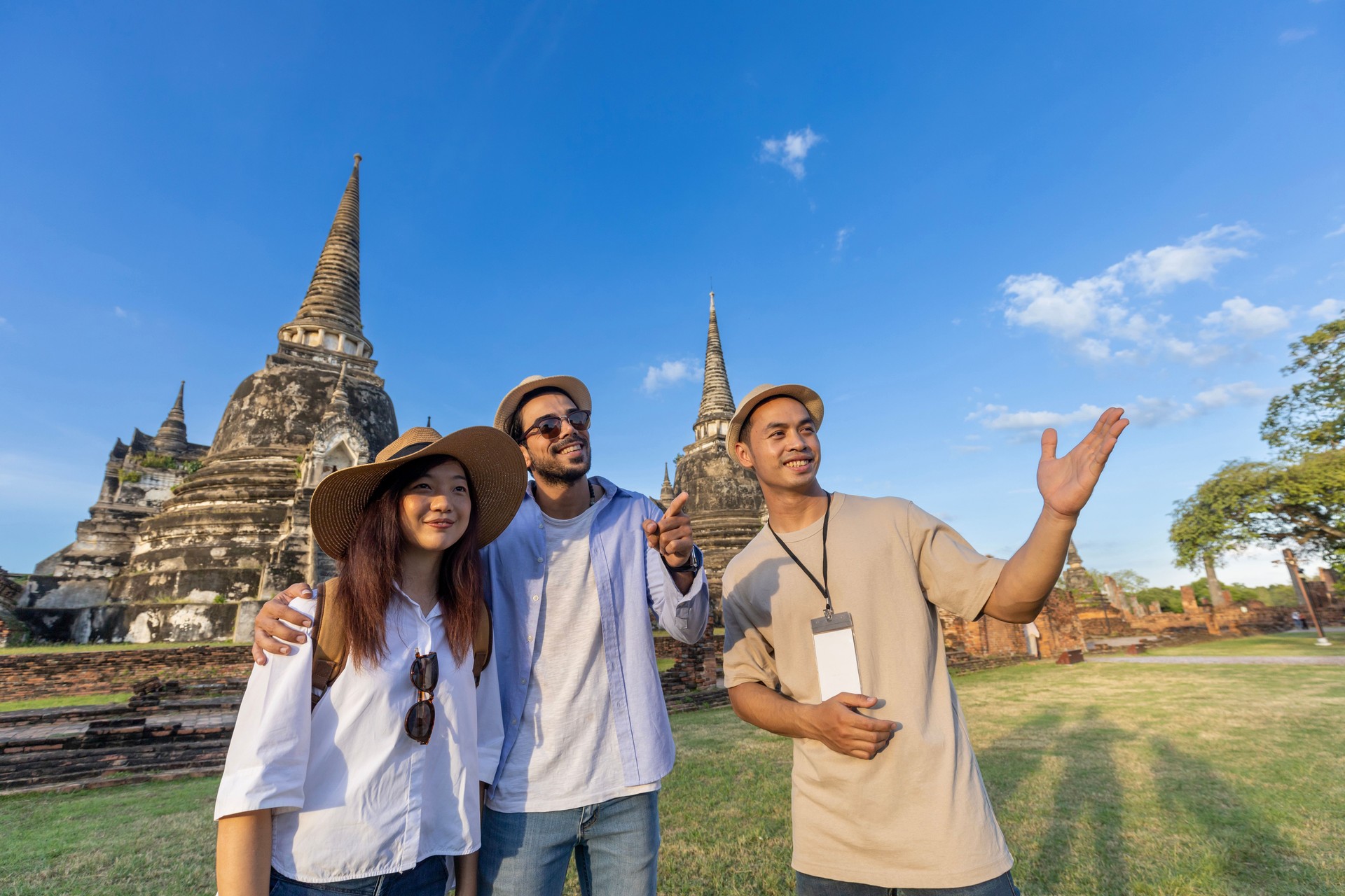 Thai local tour guide is explaining the history of old Siam to the couple of tourist on their backpacker honeymoon travel to Ayutthaya, Thailand
